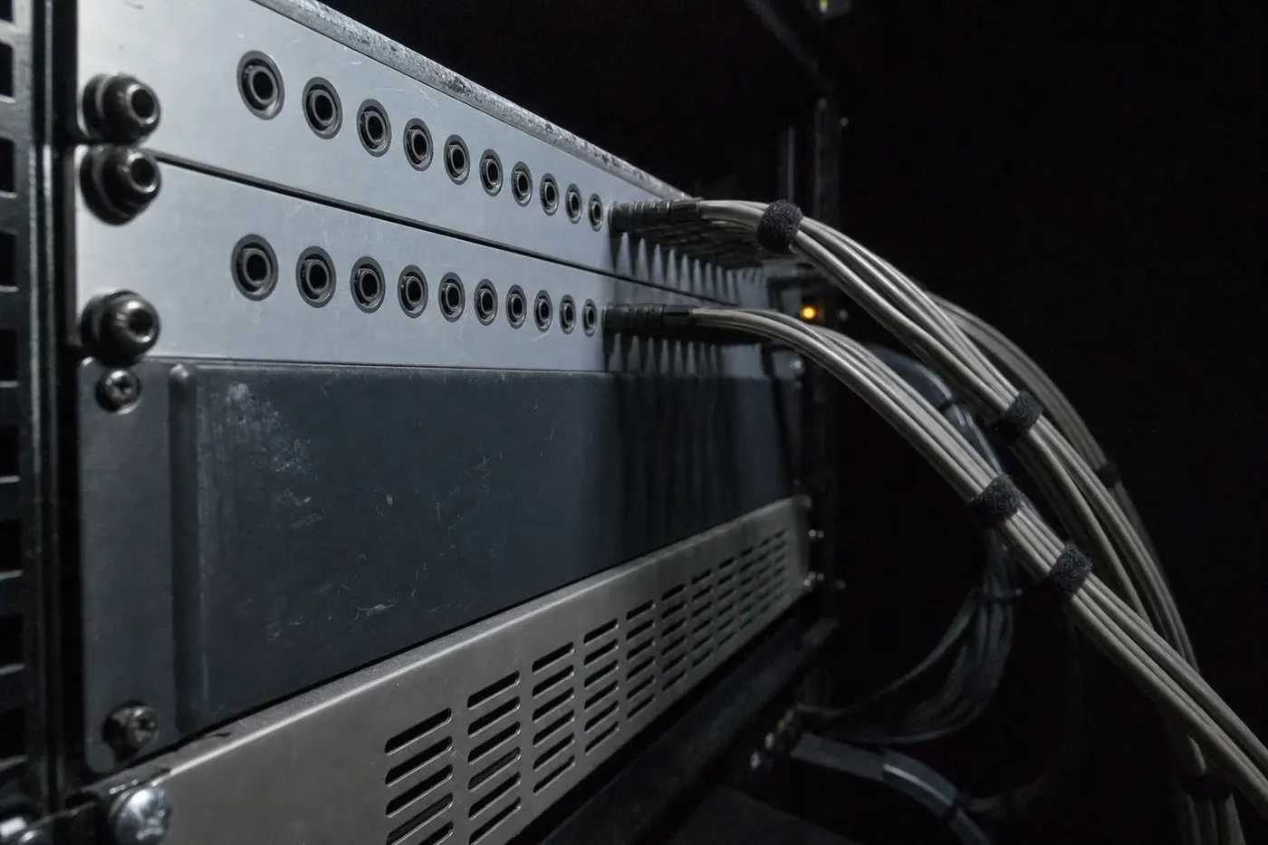 The back of a studio equipment rack, showing two rows of patch-bay jacks and cable looms dressed away to one side.